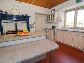A kitchen with fruit on a counter kettle and toaster near a window at Plas Gwynfryn in Llanbedr