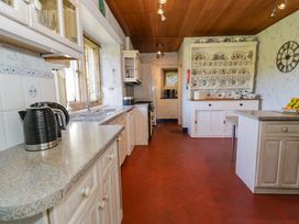 A kitchen with countertops cupboards and a kettle near a window and a cabinet with plates on display at Plas Gwynfryn in Llanbedr