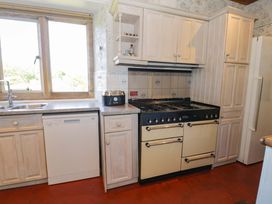A kitchen with a gas stove oven dishwasher toaster and double sink at Plas Gwynfryn in Llanbedr
