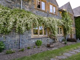 The exterior of a stone house with windows and climbing plants along the wall at Plas Gwynfryn Llanbedr