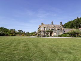 A stone house with multiple chimneys and a large lawn in front at Plas Gwynfryn in Llanbedr