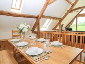 A dining table set with plates bowls glasses and cutlery under wooden beams with skylights at Shepherd's Barn Between Milborne St Andrew and Winterborne Whitechurch