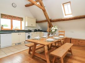 A kitchen and dining area with a wooden table set for six and exposed wooden beams at Shepherd's Barn Between Milborne St Andrew and Winterborne Whitechurch