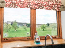 A kitchen window with a tap dish soap hand wash and sponges on the counter overlooking green grass and trees at Shepherd's Barn Between Milborne St Andrew and Winterborne Whitechurch
