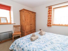 A bedroom with a bed with towels on it a wooden wardrobe a wooden chair and two windows with curtains at Shepherd's Barn Between Milborne St Andrew and Winterborne Whitechurch