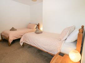 A bedroom with two single beds with pink bedding and a small wooden nightstand with a lamp at Shepherd's Barn Between Milborne St Andrew and Winterborne Whitechurch