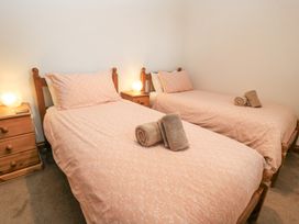 A bedroom with two single beds pink bedding and wooden nightstands with lamps at Shepherd's Barn Between Milborne St Andrew and Winterborne Whitechurch