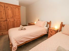 A bedroom with two single beds a wooden wardrobe and bedside tables at Shepherd's Barn Between Milborne St Andrew and Winterborne Whitechurch