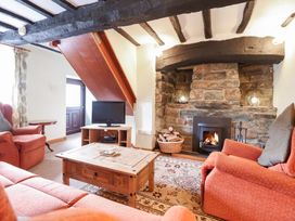 A living room with sofas a coffee table a wood burning stove and a television at Y Bwthyn in Llanbedr near Harlech