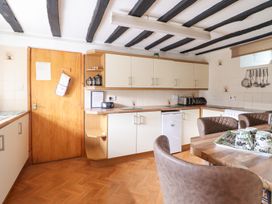A kitchen with wooden ceiling beams cabinets a wooden door and a dining table with chairs at Y Bwthyn in Llanbedr near Harlech