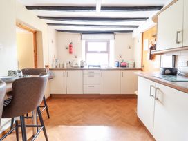 A kitchen with cabinets a window a dining table with chairs and appliances at Y Bwthyn Llanbedr near Harlech