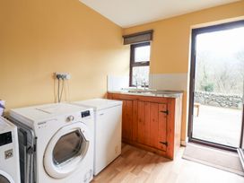 A laundry room with washing machine chest freezer wooden sink cabinet and door to outside at Y Bwthyn in Llanbedr near Harlech