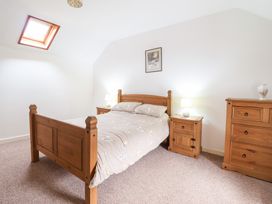 A bedroom with a wooden bed a bedside table with lamps a wooden dresser and a skylight at Y Bwthyn in Llanbedr near Harlech