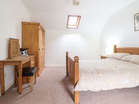 A bedroom with a wooden bed a wardrobe a dressing table and a skylight at Y Bwthyn in Llanbedr near Harlech