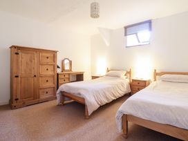 A bedroom with two single beds wooden furniture including a wardrobe desk and bedside tables at Y Bwthyn in Llanbedr near Harlech