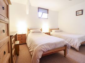 A bedroom with two single beds wooden furniture and a small window at Y Bwthyn in Llanbedr near Harlech