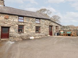 An exterior view of a stone house with multiple windows and two brown doors with outdoor seating at Y Bwthyn in Llanbedr near Harlech
