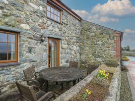An outdoor seating area with a wooden table and chairs at Daffodil Cottage Caeathro near Caernarfon