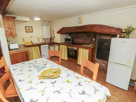A kitchen with a dining table and various appliances at Daffodil Cottage in Caeathro near Caernarfon