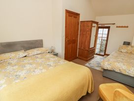 A bedroom with two beds and a wardrobe at Daffodil Cottage in Caeathro near Caernarfon
