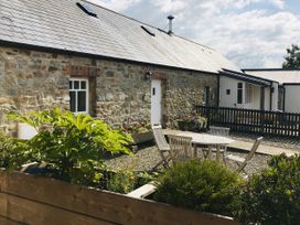 An outdoor area with stone walls, a patio table and chairs at Bwthyn Bach in Newport