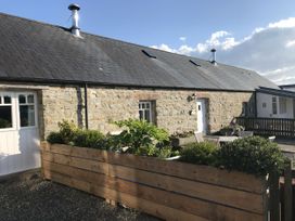 An outdoor view of a stone building with plants and a gravel area at Bwthyn Bach in Newport