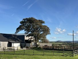 A tree and barn with a fence in the foreground at Y Cwtch Newport