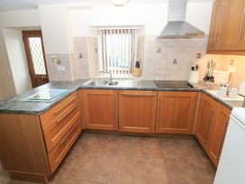A kitchen with wooden cabinets and a sink at Bwthyn Trecoed St. Clears near Carmarthen