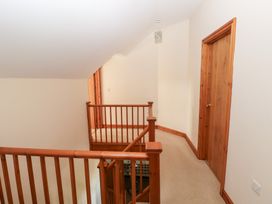 A staircase with wooden railing and door in the hallway at Bwthyn Trecoed St. Clears near Carmarthen