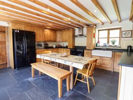 A kitchen with wooden cabinets and black appliances at Ysgubor Pwlliago in Pennant Valley near Llangynog