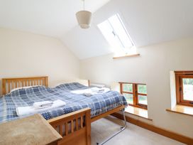 A bedroom with a bed and windows at Ysgubor Pwlliago in Pennant Valley near Llangynog