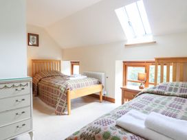 A bedroom with two beds and a bedside table at Ysgubor Pwlliago, Pennant Valley near Llangynog