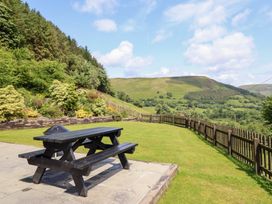 A garden with a picnic table and scenic mountains at Ysgubor Pwlliago in Pennant Valley near Llangynog