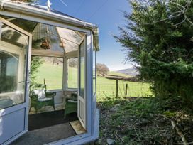 A conservatory with chairs and a view of the landscape at Penlone Cottage in Rhayader