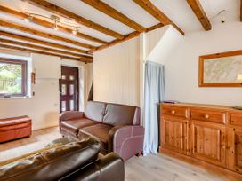 A living room with wooden beams on the ceiling brown leather sofas a wooden cabinet and a window at 3 Tyn Y Mynydd in Penmachno