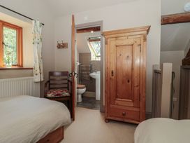 A bedroom with a bed, wardrobe and connecting bathroom at The Lodge Farm Barn in Deepdean near Ross-on-Wye