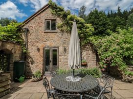 An outdoor seating area with a stone wall at The Lodge Farm Barn Deepdean near Ross-on-Wye
