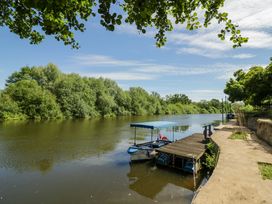 A river with a boat at a dock surrounded by trees at Severn Bank Lodge Astley Burf near Stourport-on-Severn