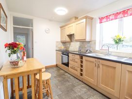 A kitchen with wooden cabinets and a table with flowers and wine at Bryn Re in Trawsfynydd near Llan Ffestiniog and Dolgellau
