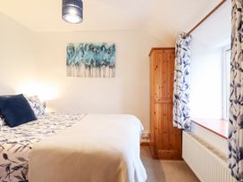 A bedroom featuring a bed, wardrobe, and window at Bryn Re in Trawsfynydd near Llan Ffestiniog and Dolgellau