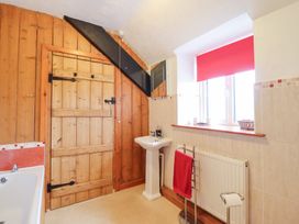 A bathroom with a sink, bathtub, and wooden door at Bryn Re Trawsfynydd near Llan Ffestiniog and Dolgellau