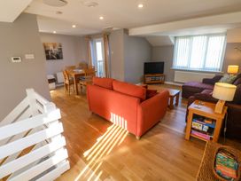 A living room with orange and purple sofas dining table wooden floors and a television at Beachcombers in Porth
