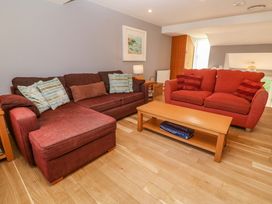 A living room with two sofas a wooden coffee table with a board game underneath and a framed picture on the wall at Beachcombers in Porth