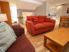 A living area with two sofas a wooden coffee table and a dining table near a kitchen at Beachcombers in Porth