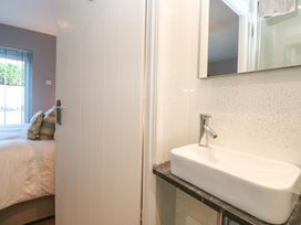 A bathroom sink with a mirror and a partially open door leading to a bedroom with a bed and pillows at Beachcombers in Porth