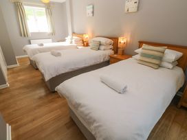 A bedroom with three single beds bedside tables and lamps at Beachcombers in Porth