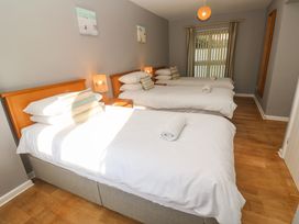 A bedroom with three single beds each with white bedding and striped pillows at Beachcombers in Porth