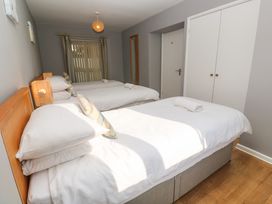 A bedroom with three beds a white wardrobe a door and a window with curtains at Beachcombers in Porth