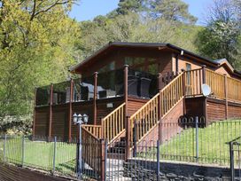 A wooden lodge with a deck and stairs at High View Lodge White Cross Bay near Troutbeck Bridge