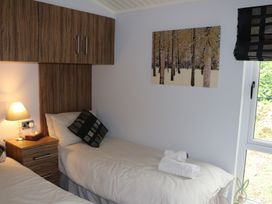 A bedroom with two beds and a bedside table at High View Lodge White Cross Bay near Troutbeck Bridge